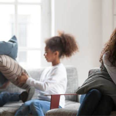 Mom who is tired and want to quit homeschooling with two children pillow fighting in the background.