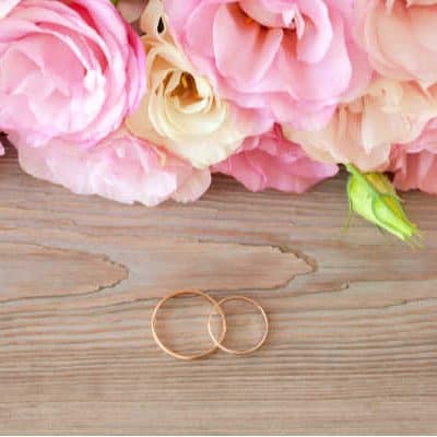 flowers with wedding rings on wood